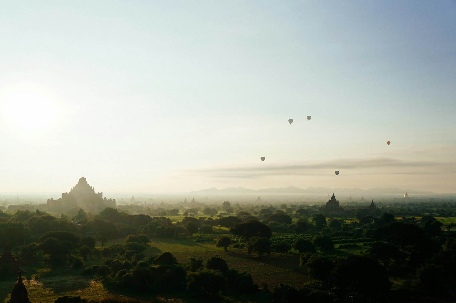 Hot air balloon floating above jungle landscape at sunrise, golden sky, aerial view of Sri Lanka