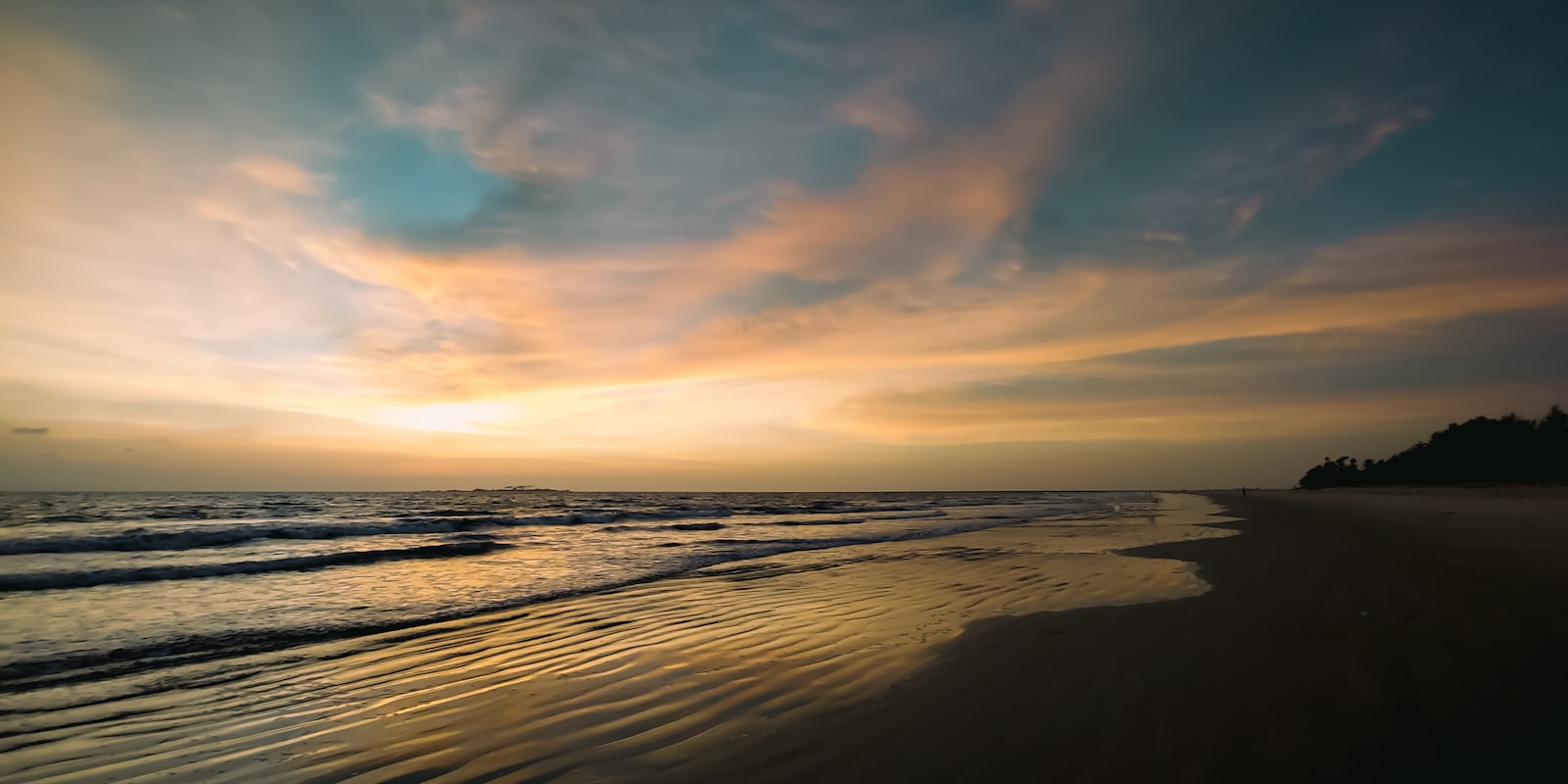 Sri Lankan beach at golden sunset, warm amber sky, calm ocean, atmospheric and moody